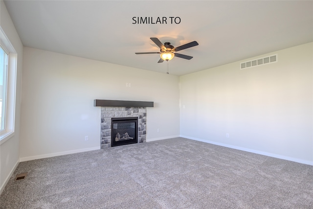 unfurnished living room featuring a stone fireplace, ceiling fan, and carpet floors