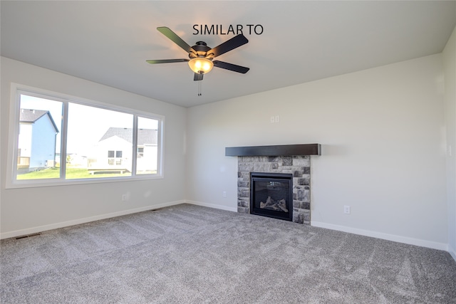 unfurnished living room featuring carpet floors, a stone fireplace, and ceiling fan