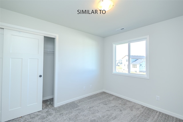 unfurnished bedroom featuring light carpet and a closet