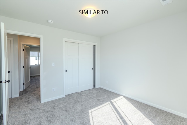 unfurnished bedroom featuring a closet and light colored carpet