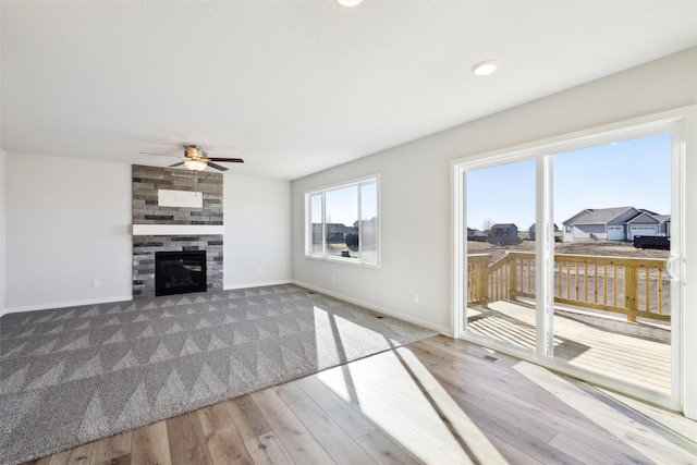 unfurnished living room with hardwood / wood-style floors, a large fireplace, and ceiling fan