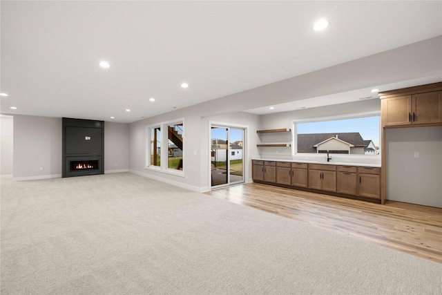 1129 NW 28th St, Grimes, IA 50111 - unfurnished living room featuring light carpet, a large fireplace, recessed lighting, and light wood finished floors
