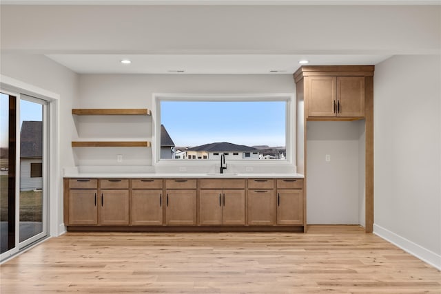 1129 NW 28th St, Grimes, IA 50111 - kitchen with brown cabinetry, light wood-style flooring, light countertops, recessed lighting, and open shelves