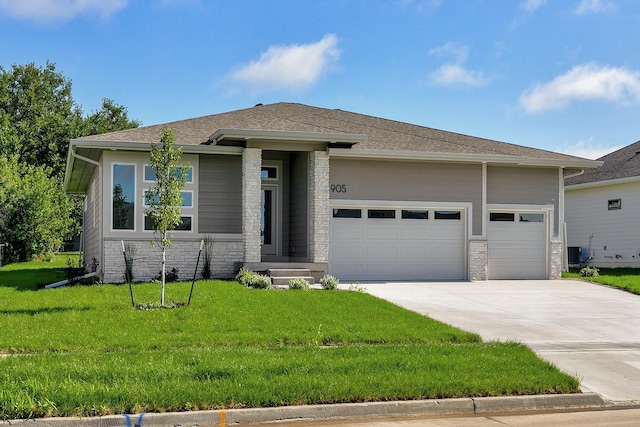 prairie-style house with a garage, stone siding, concrete driveway, and a front yard