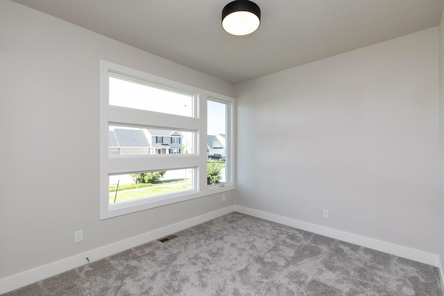 empty room with baseboards, visible vents, and carpet flooring