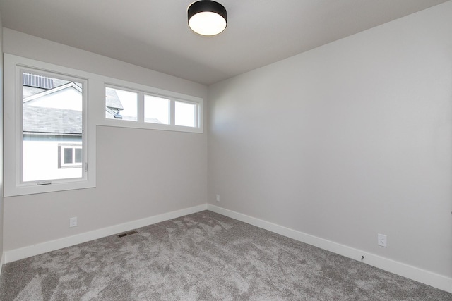 empty room with baseboards, visible vents, and carpet flooring