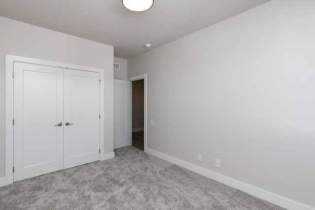 unfurnished bedroom featuring carpet, visible vents, baseboards, and a closet