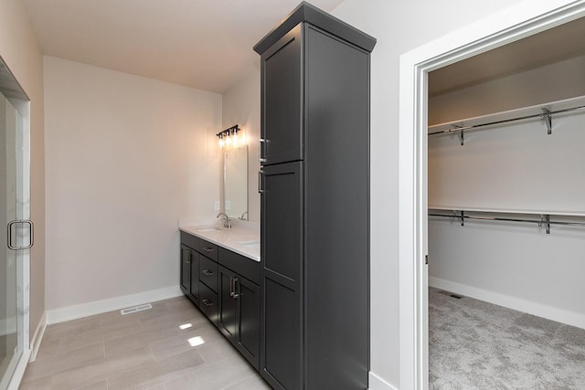 full bath with a walk in closet, visible vents, a sink, and baseboards