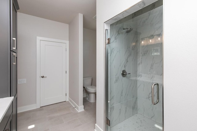 bathroom featuring baseboards, toilet, and a marble finish shower