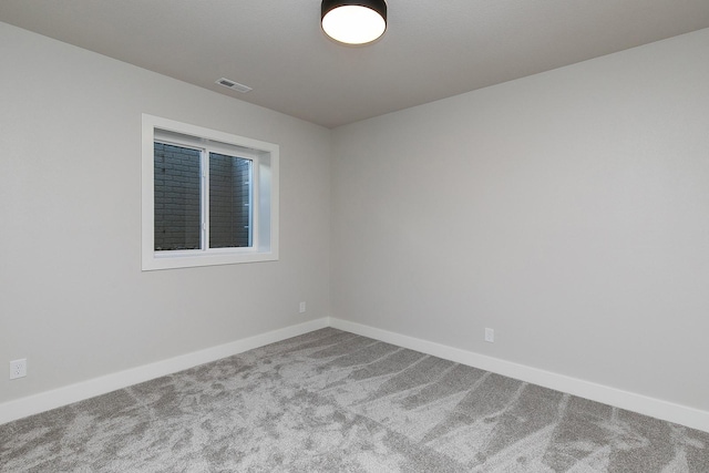 empty room featuring carpet floors, visible vents, and baseboards