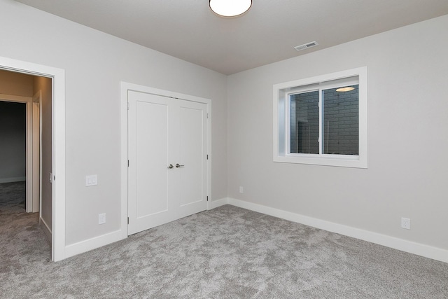 unfurnished bedroom with carpet floors, a closet, visible vents, and baseboards