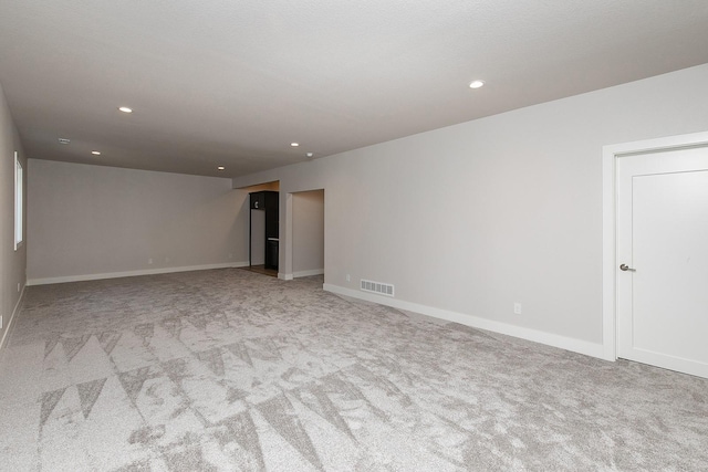 carpeted empty room with baseboards, visible vents, and recessed lighting