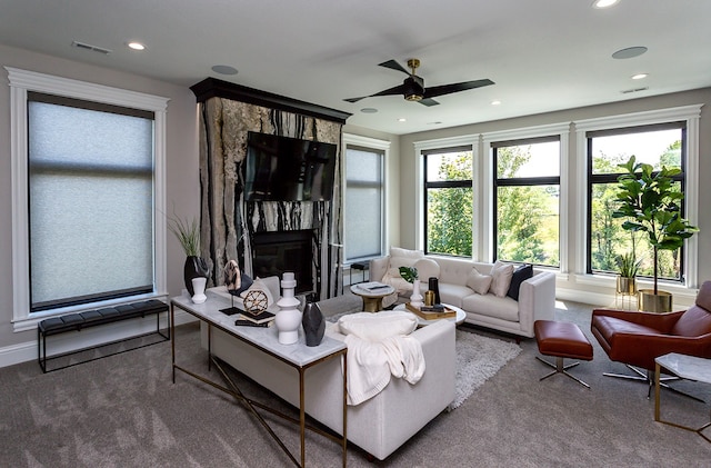 carpeted living room with a premium fireplace and ceiling fan