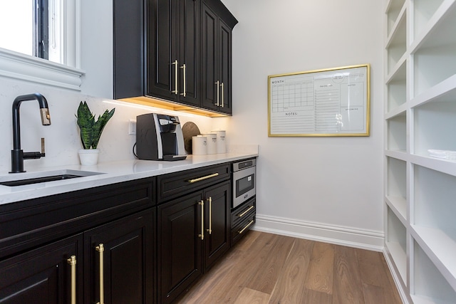 kitchen featuring light hardwood / wood-style flooring, sink, light stone countertops, and stainless steel oven