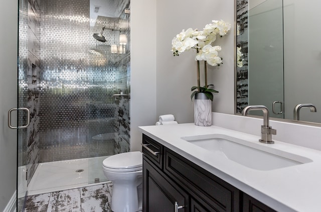 bathroom with toilet, a shower with door, and vanity