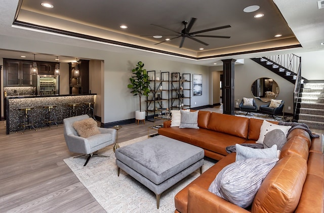 living room featuring a raised ceiling, ceiling fan, and light hardwood / wood-style floors