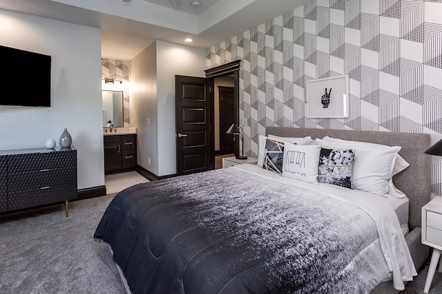 carpeted bedroom featuring ensuite bathroom and sink