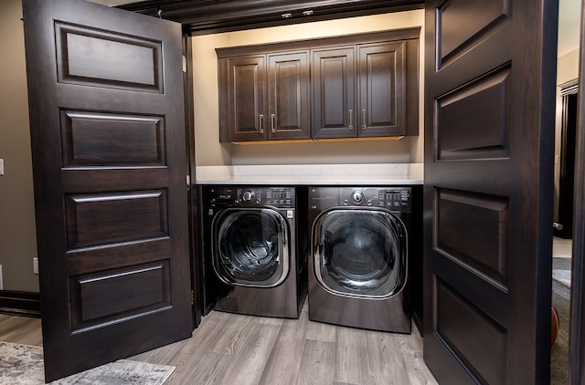 laundry area featuring cabinets, washing machine and clothes dryer, and light hardwood / wood-style floors