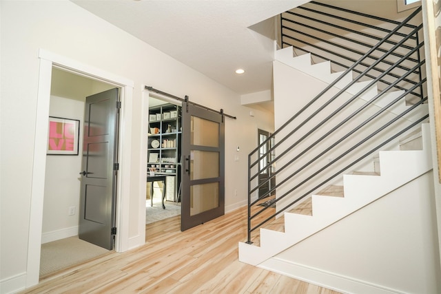 stairway featuring a barn door and hardwood / wood-style flooring