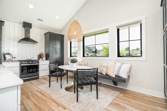 dining area with breakfast area, vaulted ceiling, and light hardwood / wood-style flooring