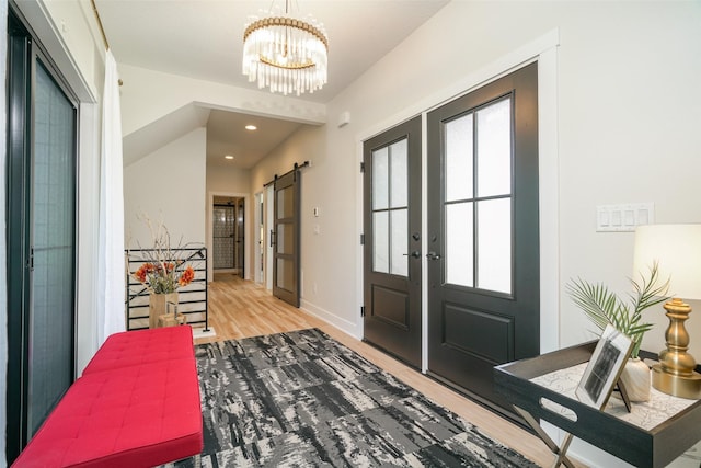 entrance foyer with a barn door, french doors, a chandelier, and hardwood / wood-style flooring