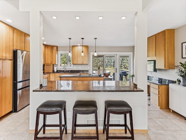 kitchen with stainless steel fridge, a kitchen island, a breakfast bar area, and a sink