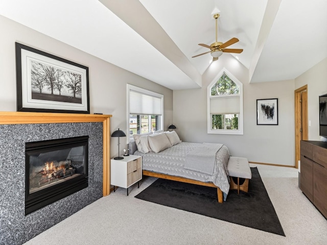 carpeted bedroom featuring ceiling fan, baseboards, vaulted ceiling, and a glass covered fireplace