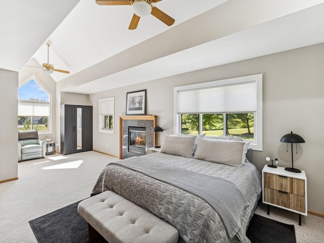 carpeted bedroom featuring lofted ceiling, multiple windows, baseboards, and a tile fireplace