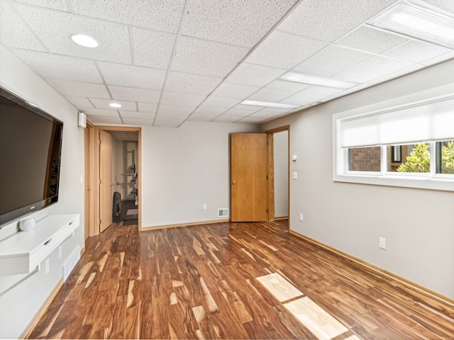 unfurnished living room with a paneled ceiling and dark hardwood / wood-style flooring