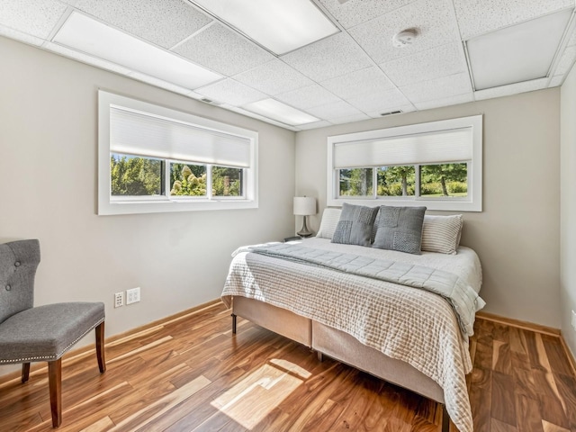 bedroom with multiple windows, baseboards, and wood finished floors