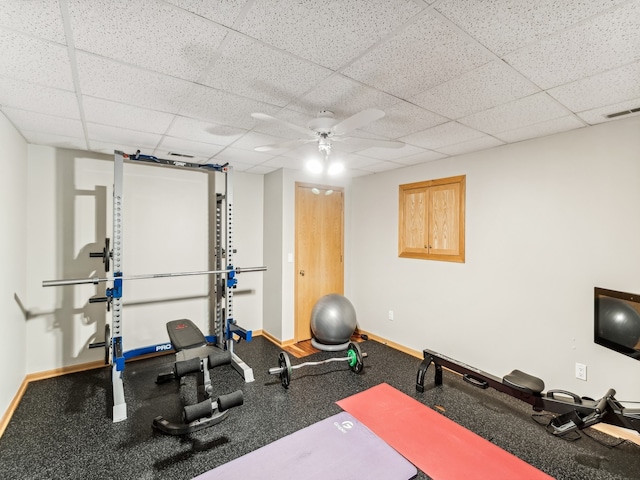 exercise room with a paneled ceiling and ceiling fan