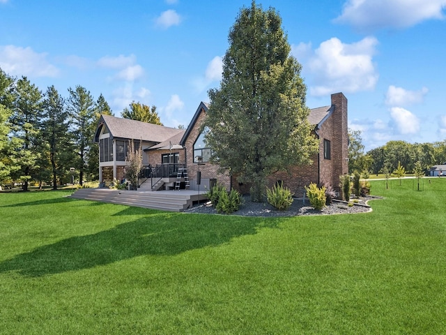 rear view of house featuring a deck, a lawn, a chimney, and a sunroom