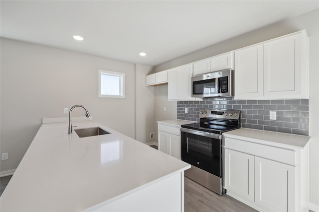 kitchen featuring sink, light wood-type flooring, white cabinetry, decorative backsplash, and stainless steel appliances