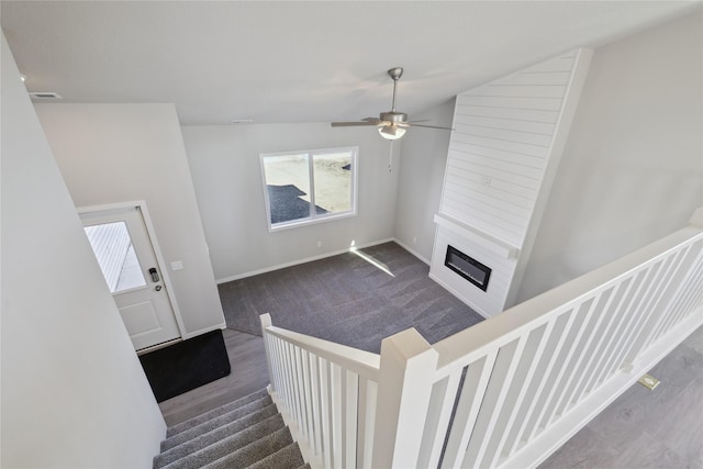 living room featuring ceiling fan, dark carpet, a large fireplace, and vaulted ceiling