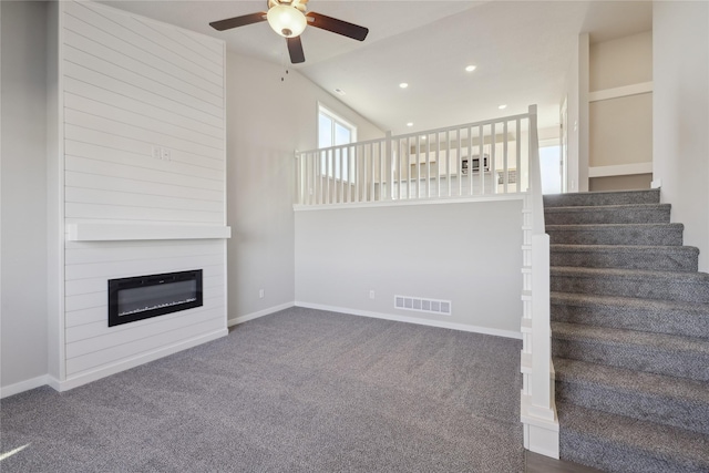 unfurnished living room with ceiling fan, dark carpet, lofted ceiling, and a fireplace