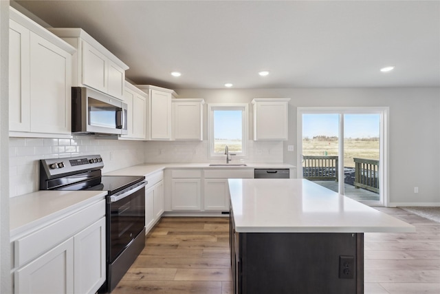 kitchen featuring stainless steel appliances, white cabinetry, sink, and light hardwood / wood-style floors