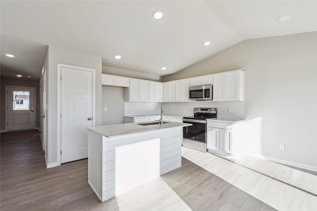 kitchen with white cabinets, stainless steel appliances, a kitchen island with sink, and sink