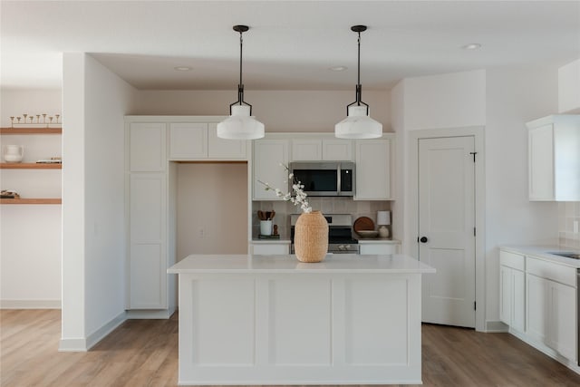 kitchen with decorative light fixtures, a center island, light wood-type flooring, and stainless steel appliances