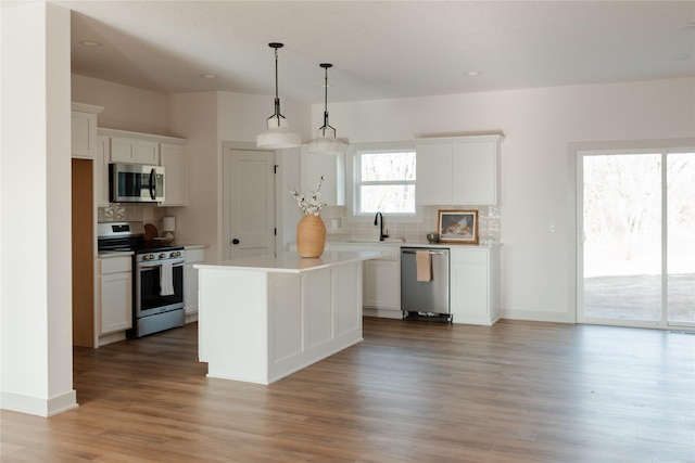 kitchen with hanging light fixtures, a center island, white cabinets, and stainless steel appliances