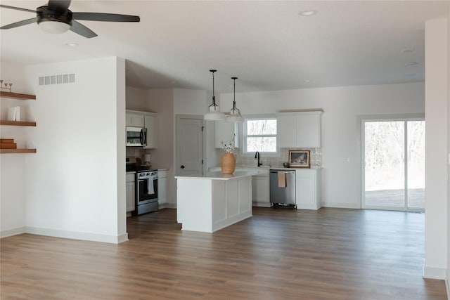 kitchen featuring pendant lighting, a center island, white cabinets, hardwood / wood-style flooring, and stainless steel appliances