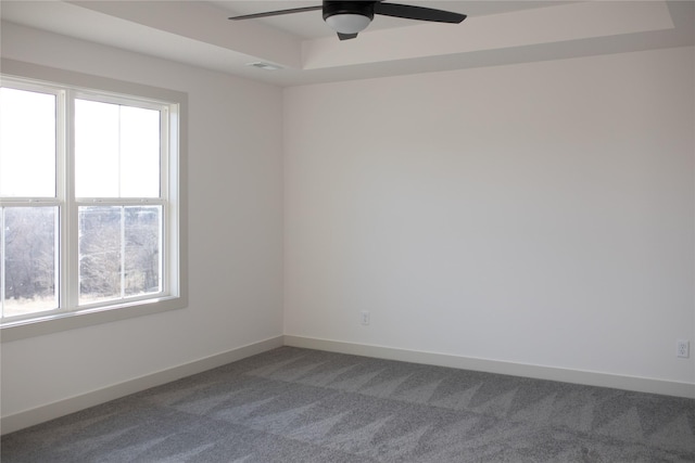 carpeted empty room with ceiling fan and a raised ceiling