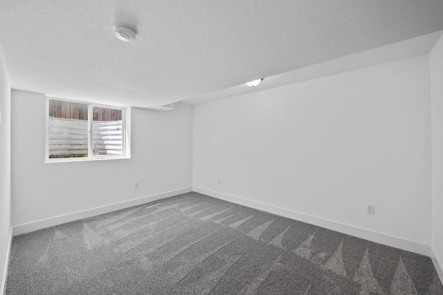 unfurnished room featuring a textured ceiling, baseboards, and dark colored carpet