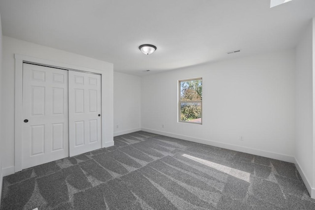 unfurnished bedroom featuring visible vents, baseboards, a closet, and carpet flooring