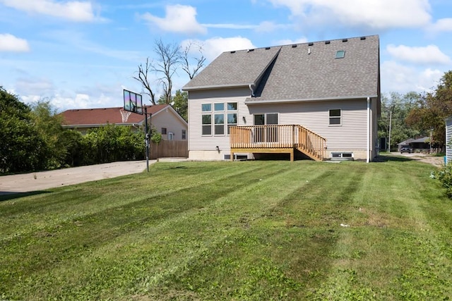 rear view of house with a deck, a yard, and a shingled roof