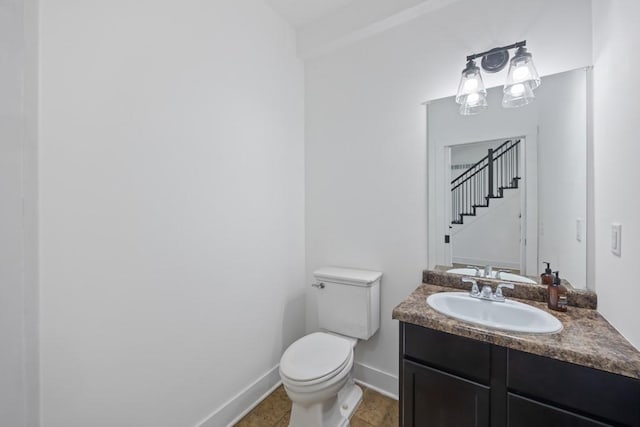 bathroom with toilet, vanity, and baseboards