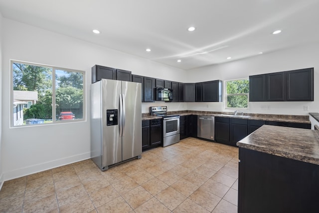 kitchen with light tile patterned floors, a healthy amount of sunlight, stainless steel appliances, and sink