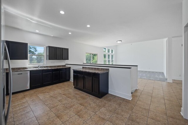 kitchen featuring light tile patterned flooring, recessed lighting, a sink, stainless steel appliances, and dark cabinets