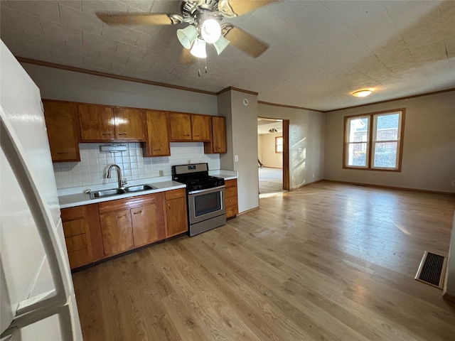 kitchen featuring sink, stainless steel range, light hardwood / wood-style flooring, and crown molding