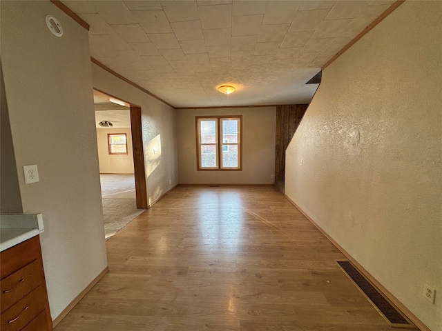 unfurnished room featuring crown molding and light wood-type flooring