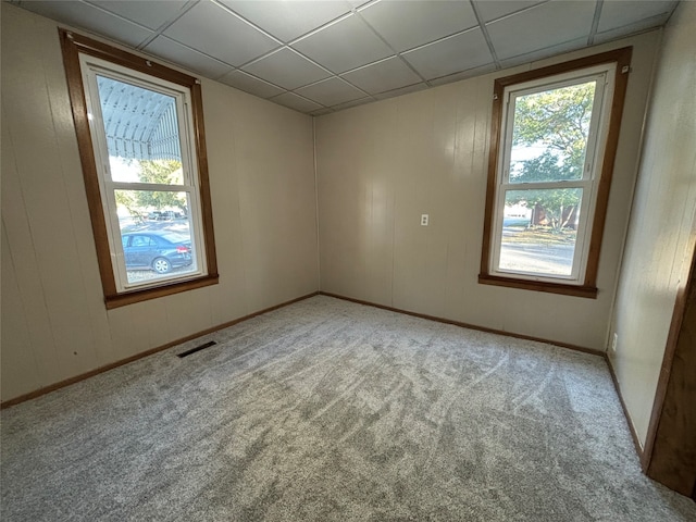 empty room featuring a drop ceiling and light colored carpet